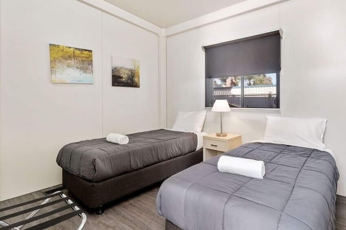 A hotel room with two beds, a window with a view, and artwork on the walls.