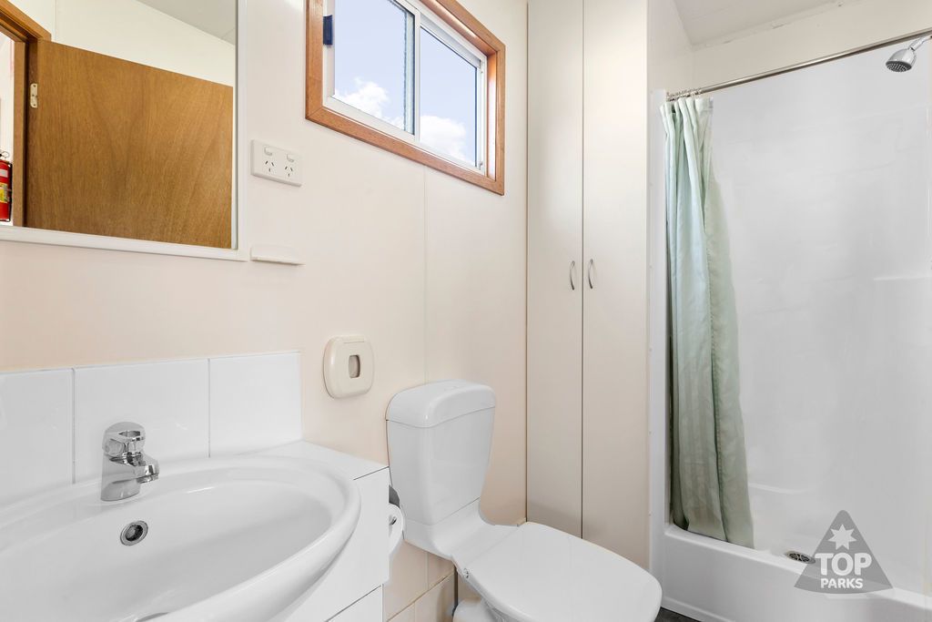 A bathroom with a white sink, toilet, and shower curtain.
