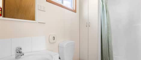 Un baño con lavamanos blanco, inodoro y cortina de ducha.