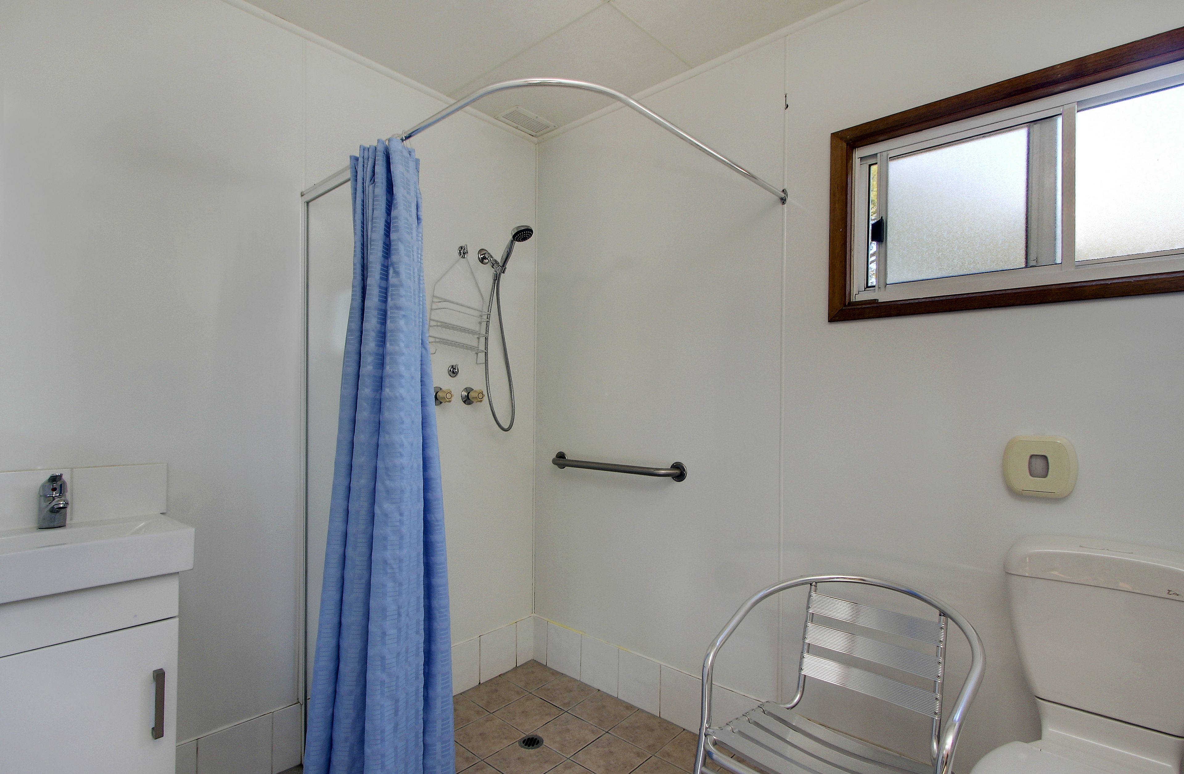 A bathroom with a shower, a toilet, a sink, and a mirror.