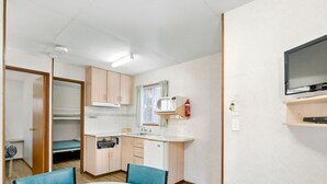 Una cocina compacta equipada con microondas, pileta y televisor instalado en la pared.