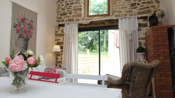 A cozy room with a stone wall, a wooden bench, a wicker chair, and a vase of flowers on a table. - The closed Hellen .... (monterblanc)