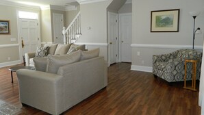 A living room with a beige sofa, patterned armchair, and a wooden floor. - PERFECT LISTING !!! House in Historic Chickamauga (Chickamauga)