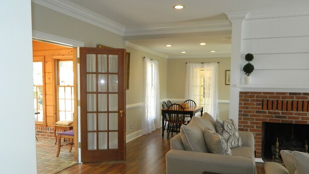 A spacious living room with hardwood floors, a fireplace, a dining area with a table and chairs, and a large door leading to an outdoor area. - PERFECT LISTING !!! House in Historic Chickamauga (Chickamauga)