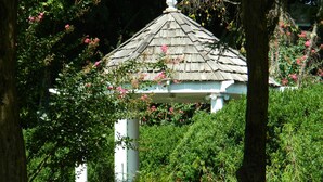 A gazebo with a white roof and columns, surrounded by lush greenery and flowering bushes. - PERFECT LISTING !!! House in Historic Chickamauga (Chickamauga)