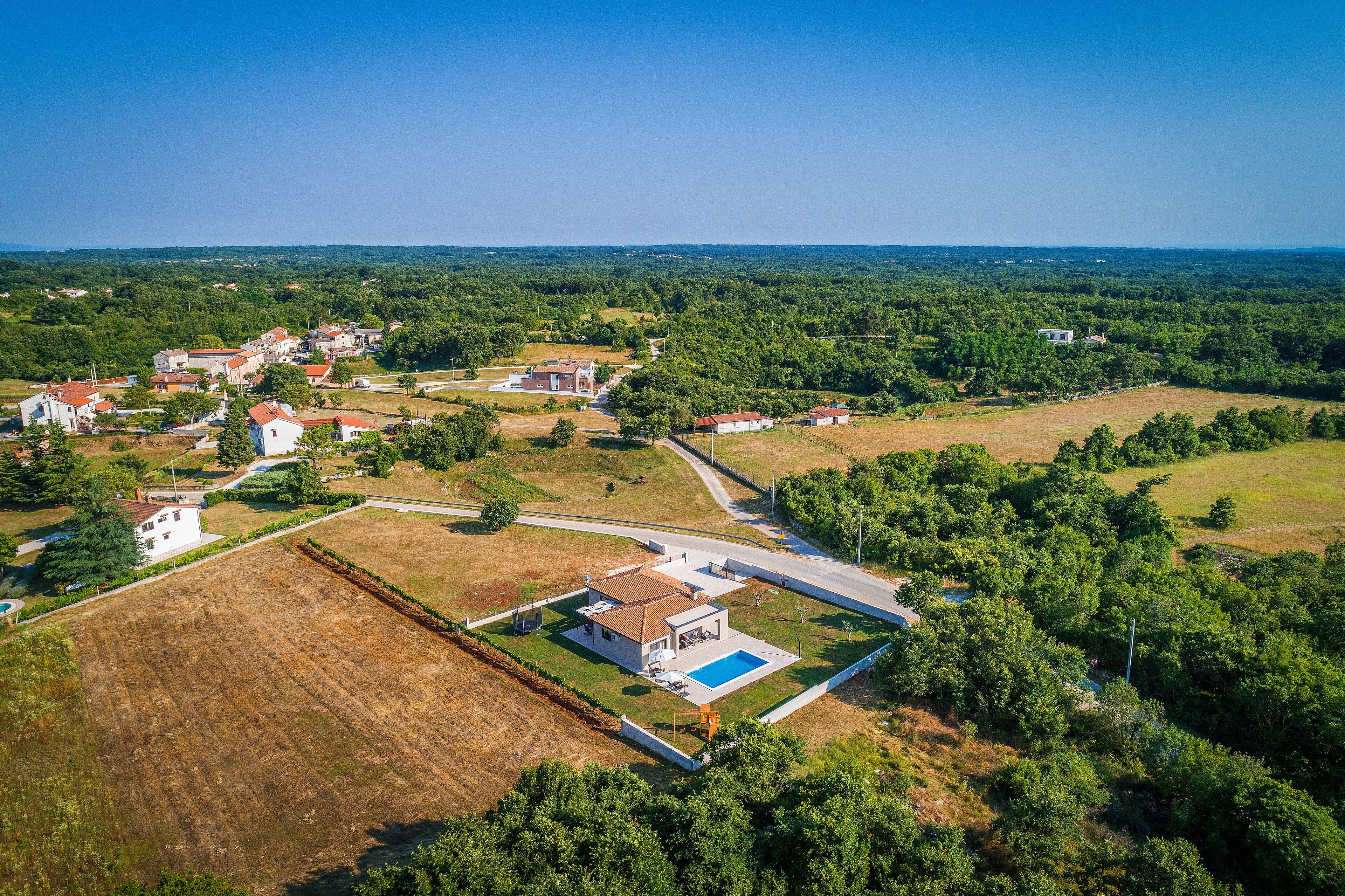 Vista aèria d'una zona residencial amb cases, una piscina i vegetació als voltants.