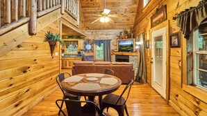 A wooden cabin interior with a dining area, living room, and kitchen. - Indoor Pool Cabin  | Romantic | Sleeps 4 (Sevierville)
