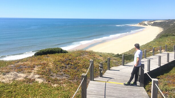 Une promenade en bois qui mène à une plage d’où l’on a une vue dégagée sur l’océan.