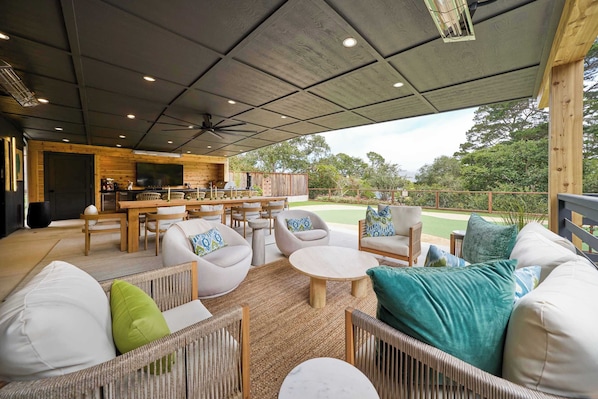 Un patio al aire libre con mobiliario de mimbre, una barra y vistas de la vegetación circundante.