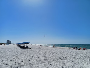 Guests can enjoy a beachside retreat with umbrellas providing shade and a view of the calm sea.