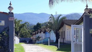 A gated entrance to a property with numbered signs, a gravel driveway, and buildings with tiled roofs.