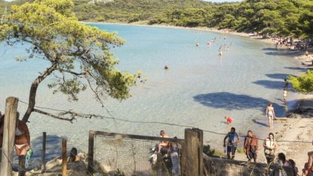 A beach with clear water, people swimming and walking, and a forested hill in the background. - Apartment near the sea (Hyères)