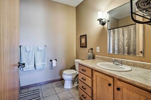 Ein Badezimmer mit Toilette, Waschbecken, Waschtisch, Handtuchhalter und Spiegel.