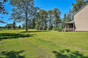 A house with a porch, surrounded by a well-maintained lawn and tall trees.