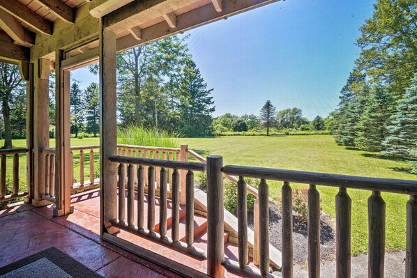 A covered porch with a view of a well-maintained lawn and trees.