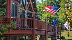 Een lodge met een houten terras, stenen pilaren en een Amerikaanse vlag.