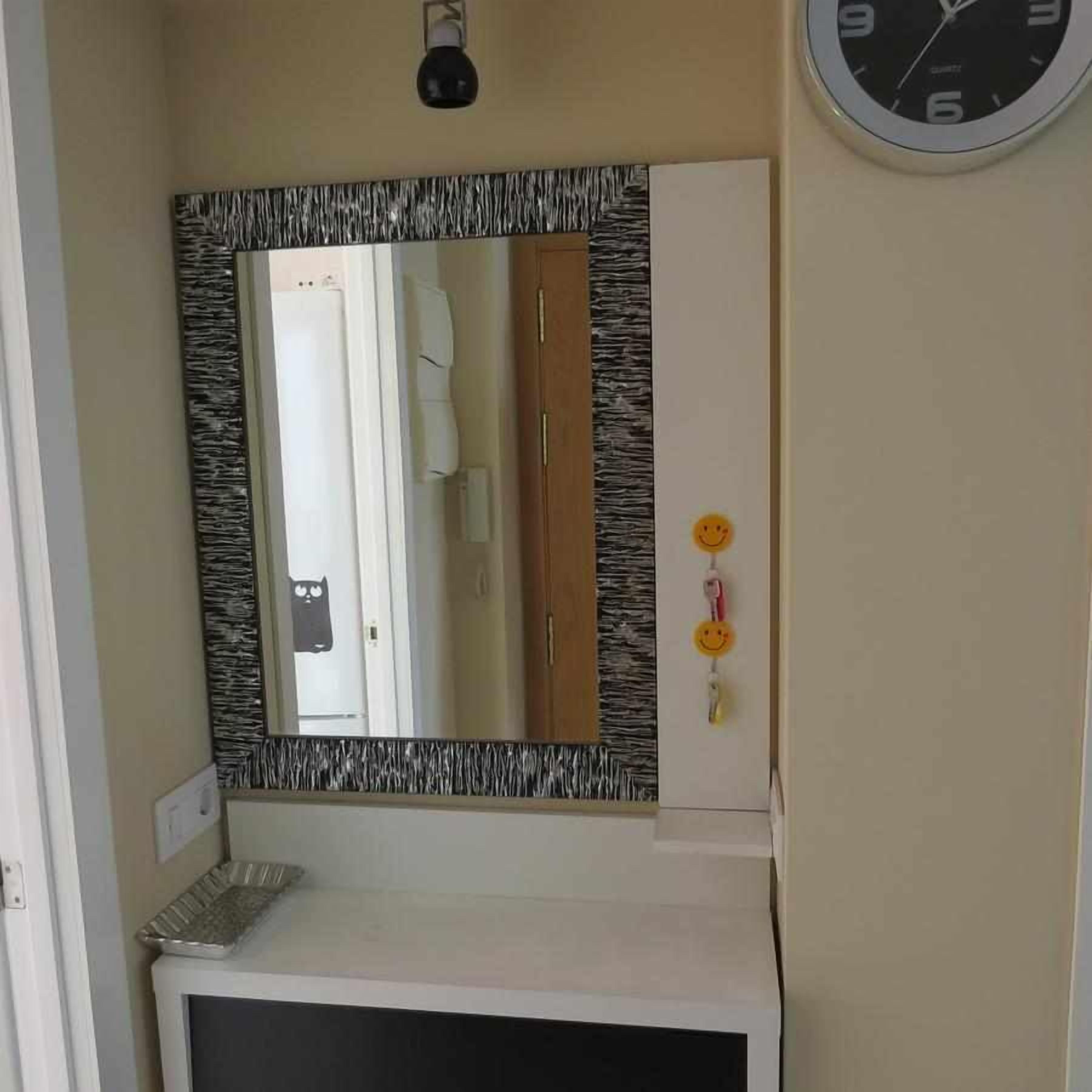 A bathroom with a mirror, a clock, and a towel rack.