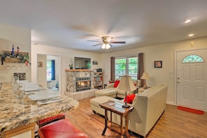 A living room with a fireplace, a television, a sofa, and a dining area with a marble countertop.