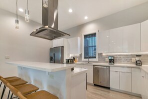 A modern kitchen with a central island, stainless steel appliances, and pendant lighting.