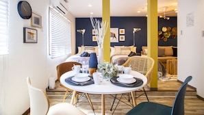 Ein modernes Wohnzimmer mit Essbereich, ausgestattet mit einem runden Tisch für vier Personen, einer Couch und einem Couchtisch.