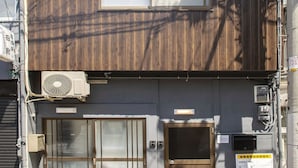 Ein zweistöckiges Gebäude mit Holzfassade, einer Schiebetür und einer kleinen Klimaanlage.