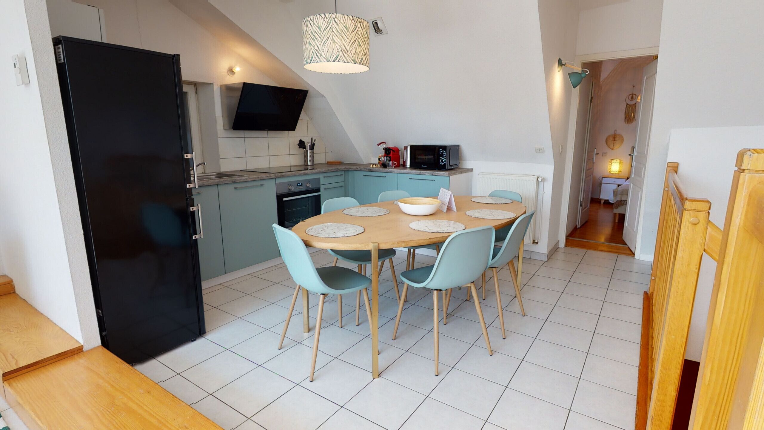 A compact kitchen with a dining area, a black refrigerator, a microwave, and a built-in oven.