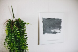 A white wall with a framed abstract painting and a hanging green plant. - Japanese Modern Room Tenma (Osaka)