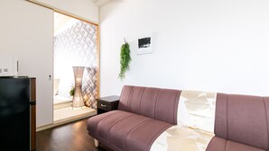 A modern living room with a sofa, a small table, and a refrigerator. - Japanese Modern Room Tenma (Osaka)