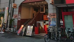 A building with a red and white facade, a visible entrance, and several bicycles parked outside. - Japanese Modern Room Tenma (Osaka)