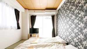 A room with two beds, a television on a wooden stand, and a window with curtains. - Japanese Modern Room Tenma (Osaka)