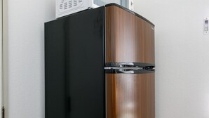 A compact refrigerator with a microwave on top, positioned against a white wall with a wooden floor. - Japanese Modern Room Tenma (Osaka)
