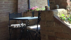 A rustic outdoor seating area with a brick wall, wooden beams, and a hanging lantern. - THE FRANCIGENA TWO-ROOM CUSTOMS (Siena)