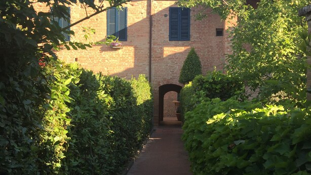 A narrow brick pathway leading to a traditional brick building with a small archway. - THE FRANCIGENA TWO-ROOM CUSTOMS (Siena)