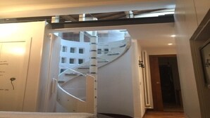 A modern hotel room with a spiral staircase leading to an upper floor, a bed with a patterned bedspread, and a wooden floor. - THE FRANCIGENA TWO-ROOM CUSTOMS (Siena)