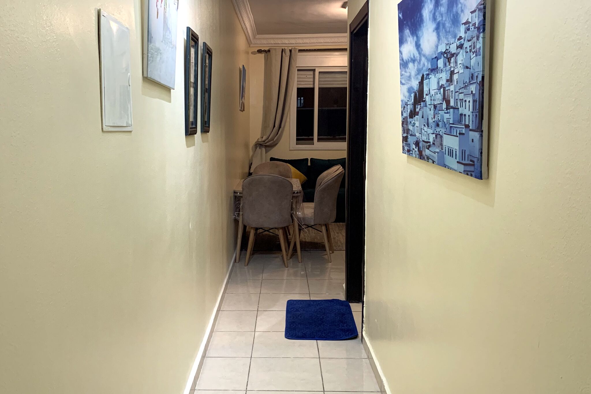 A narrow hallway with a dining area at the end, featuring a table and chairs.
