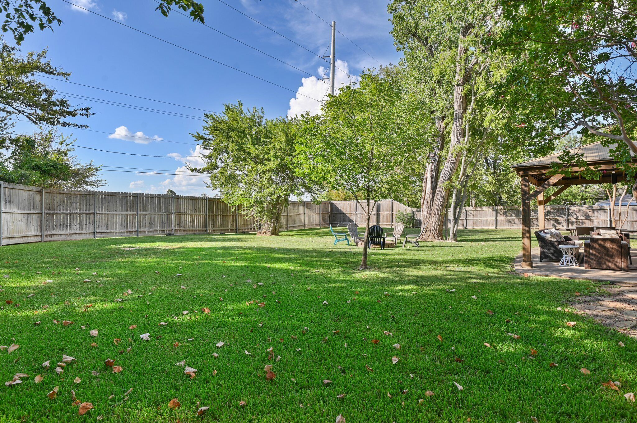 A backyard with a wooden fence, a pergola, and outdoor furniture.