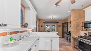 Una cocina con armarios blancos, una isla grande, una estufa y un microondas.