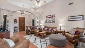 Un salón espacioso con techo alto, ventilador de techo y un gran letrero en la pared que dice "TEXAS A&M".