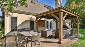 Un espacio de patio al aire libre con un pérgola, una parrilla y un juego de comedor.