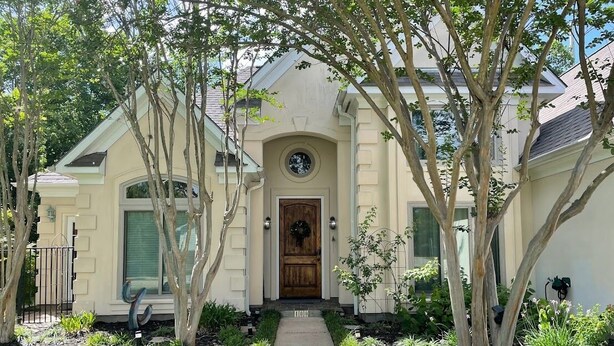 Una casa con entrada principal, un camino que lleva a la puerta y un jardín con plantas y árboles.