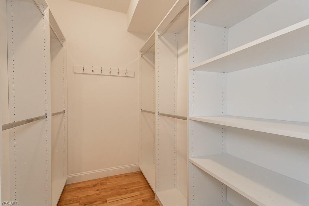 A walk-in closet with open shelving and a wooden floor.