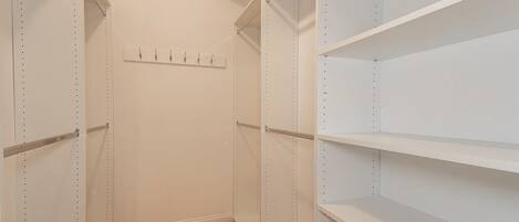 A walk-in closet with open shelving and a wooden floor.