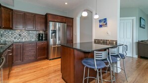 Une cuisine moderne avec des meubles de couleur bois foncé, un réfrigérateur en acier inoxydable et un grand îlot central doté de tabourets de bar.