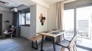 A modern living room with a wooden dining table, two chairs, a bench, and a wall-mounted air conditioner. - GroundFloor Apartment w/Smallyard in the ❤ of Kalamata (Kalamata)