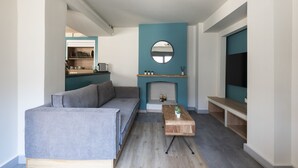 A modern living room with a grey sofa, a wooden coffee table, and a teal accent wall with a fireplace. - GroundFloor Apartment w/Smallyard in the ❤ of Kalamata (Kalamata)