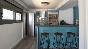 A modern kitchen with a built-in island, bar stools, and a stainless steel refrigerator. - GroundFloor Apartment w/Smallyard in the ❤ of Kalamata (Kalamata)
