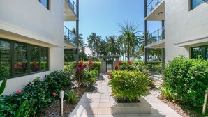 Un bâtiment moderne doté de grandes fenêtres et d’un jardin bien entretenu, où l’on trouve une variété de plantes et de fleurs.