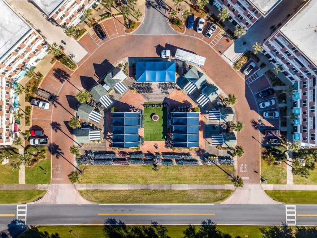 Vista aérea de una zona comercial con un espacio verde central, estacionamientos y edificios circundantes.