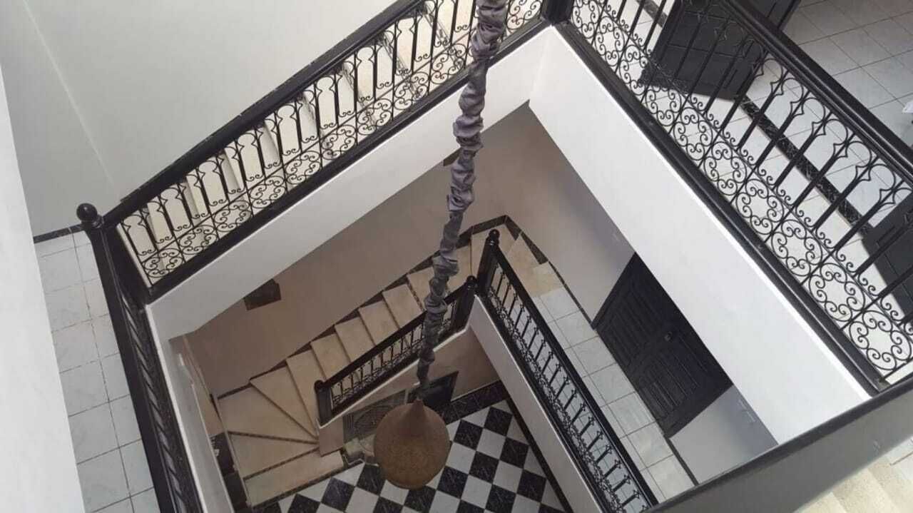A multi-level interior with a black and white checkered floor, a central column, and ornate black railings.