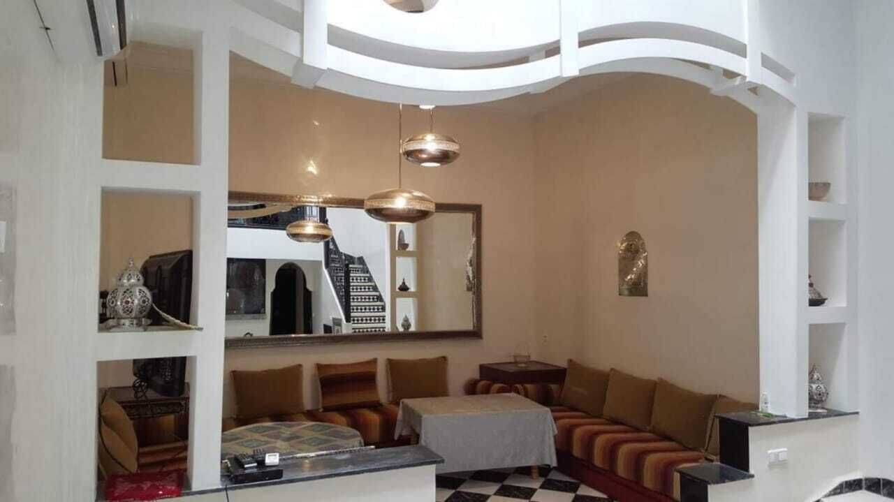 A modern living room with a sofa set, a dining table, and a large mirror.
